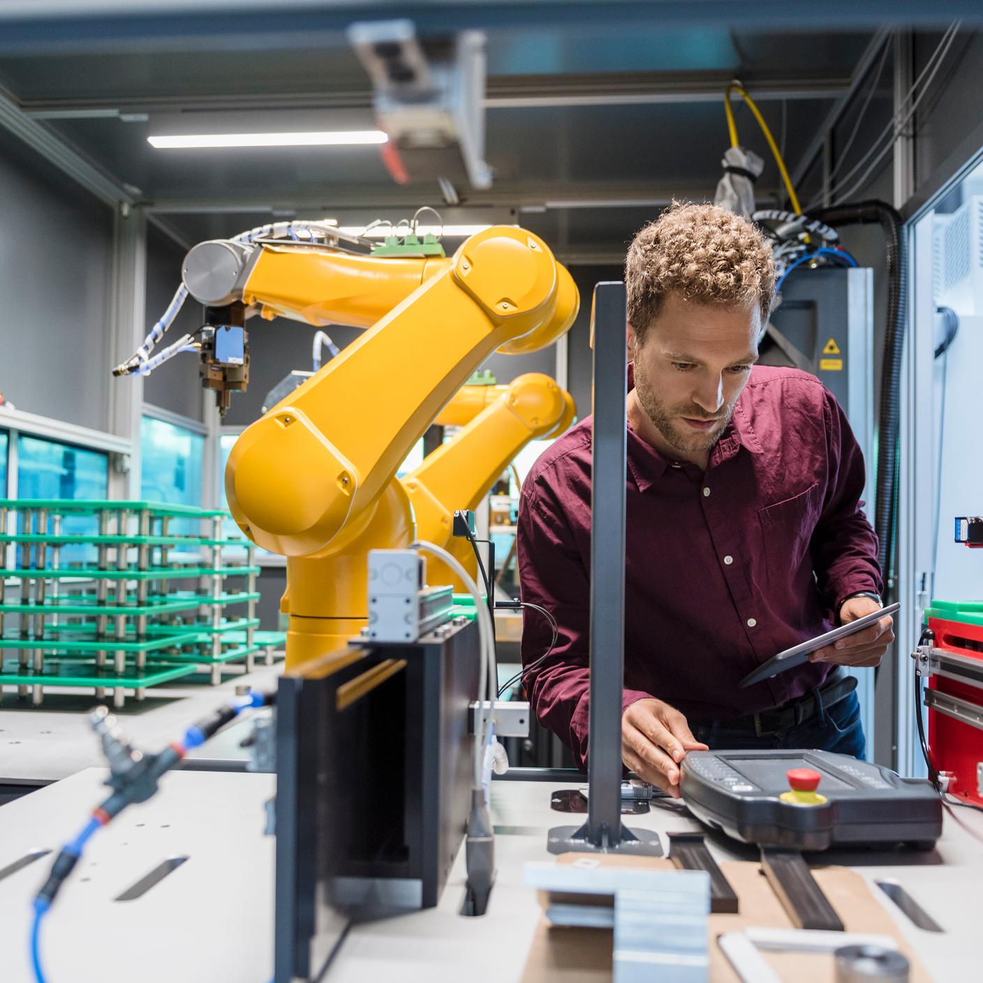 Ethische und vertrauenswürdige künstliche Intelligenz - Geschäftsmann prüft Industrieroboter in Hightech-Unternehmen