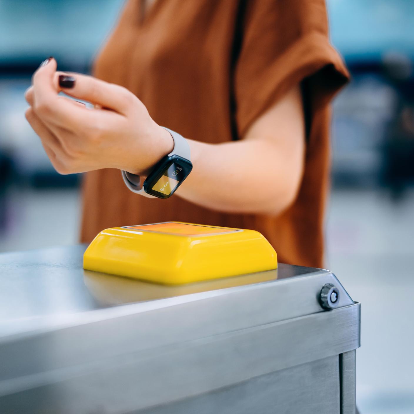 Eine Frau checkt an einer U-Bahn-Station ein und bezahlt ihr U-Bahn-Ticket kontaktlos über ihre Smartwatch.