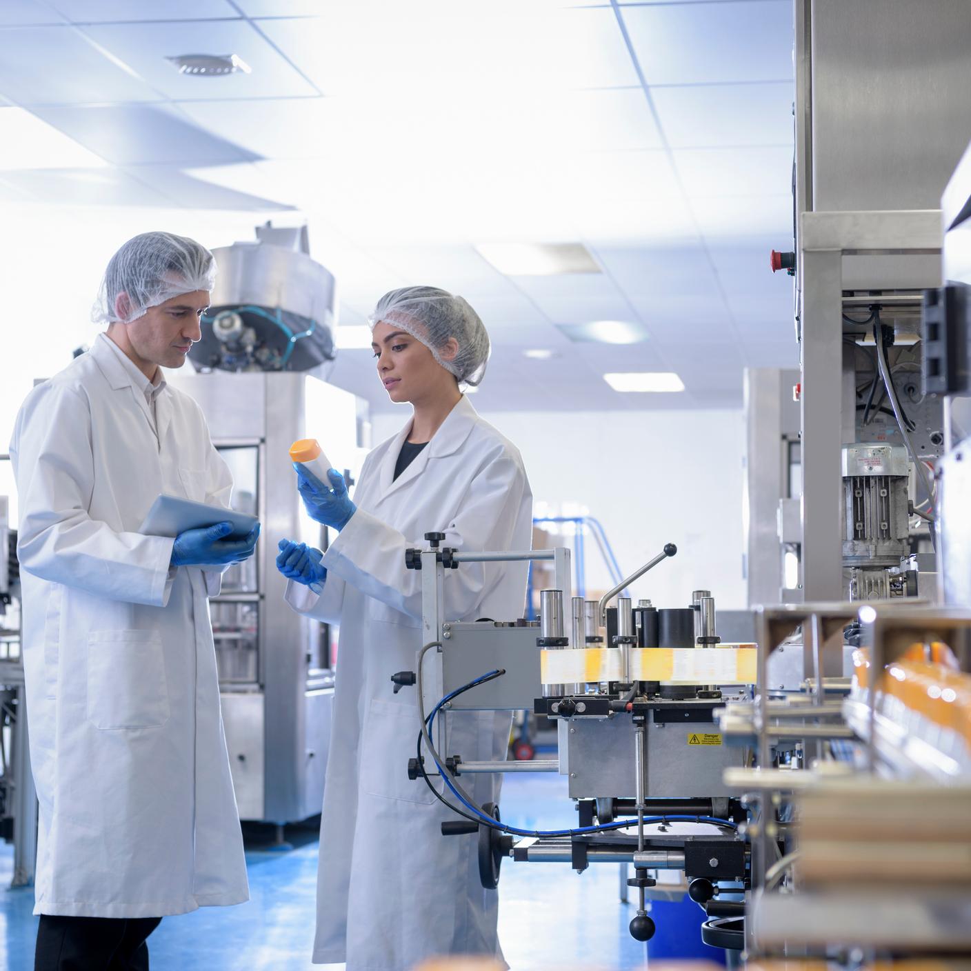 Workers inspecting product in pharmaceutical factory.